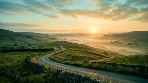 Country road winding through hills at sunrise