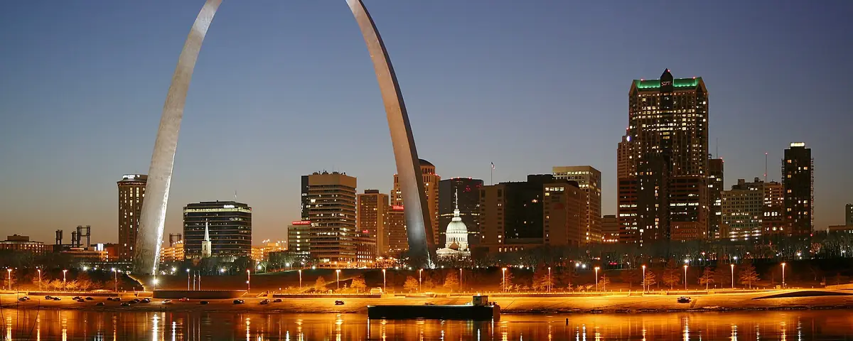 Missouri: St. Louis on the Mississippi river by night. Jefferson National Expansion Memorial aka. Gateway Arch and Old Courthouse are visible.